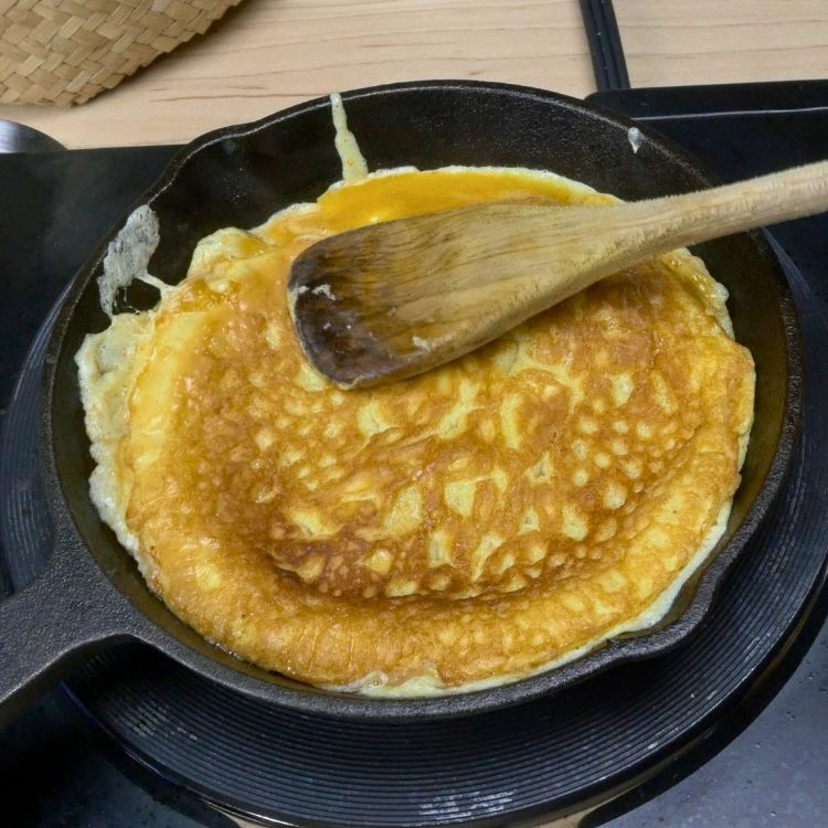 Golden brown chili egg omelette after being flipped in the cast iron pan