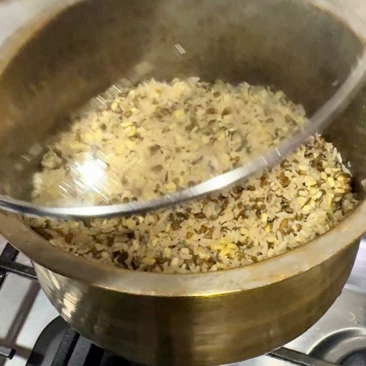 Freshly cooked, fluffy high-protein rice with visible grains of white rice and split green moong dal after removing the lid.