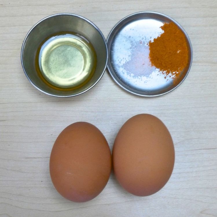 Fresh eggs, chili powder, salt and cooking oil arranged on a table for making a quick omelette