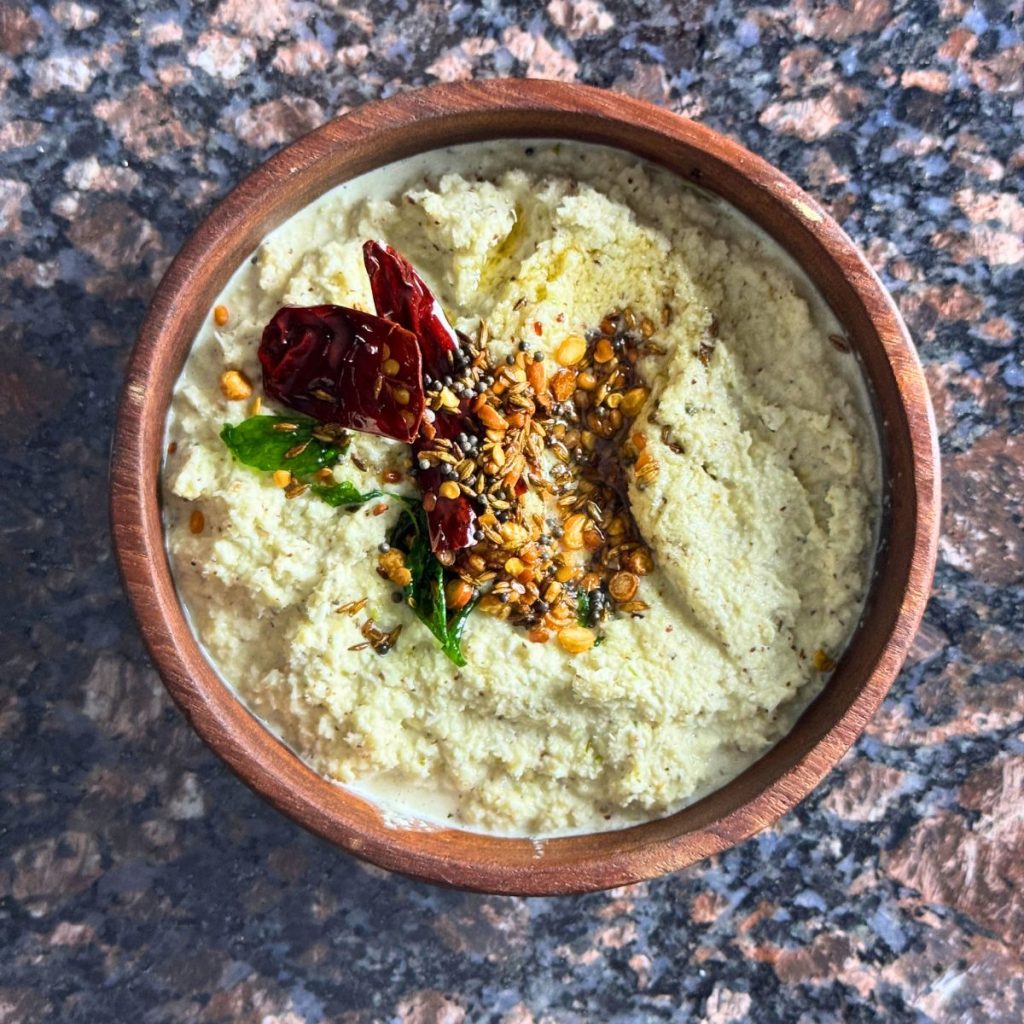 A bowl of creamy coconut chutney garnished with tempered spices, served as a side dish for idlis or dosas.