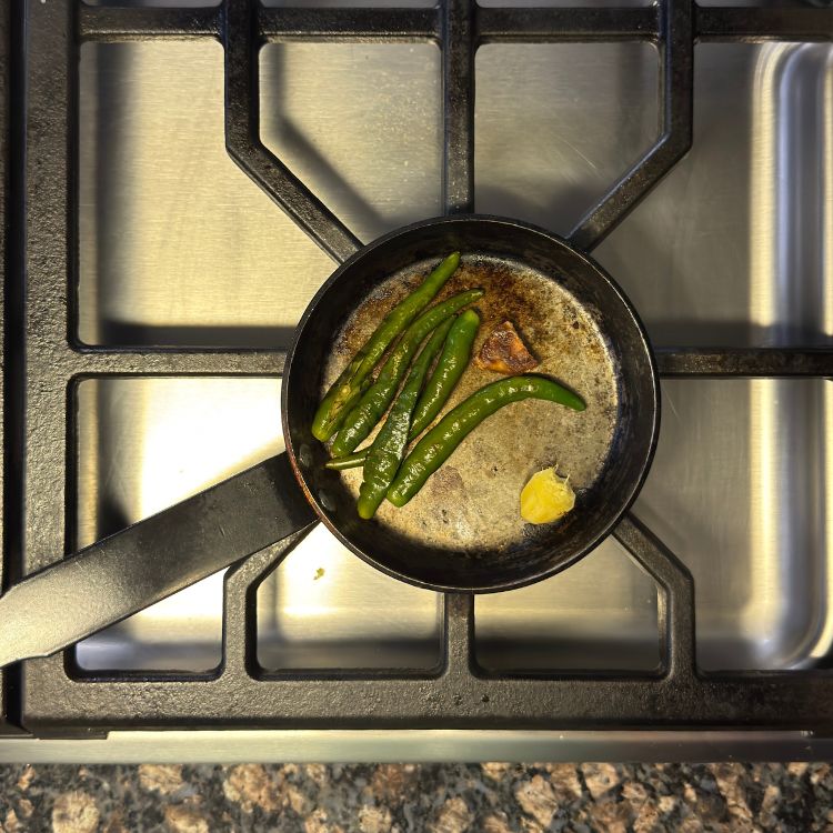Green chilies blistering on a hot pan, releasing their aroma for the coconut chutney recipe.