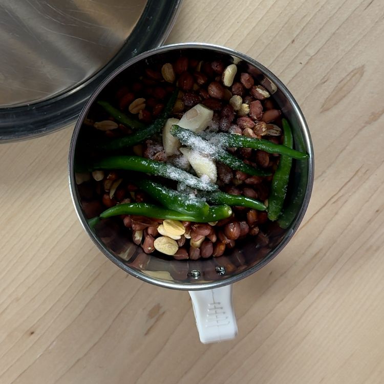 Roasted peanuts, green chilies, garlic, and salt prepared in a grinder ready to be blended into smooth peanut chutney