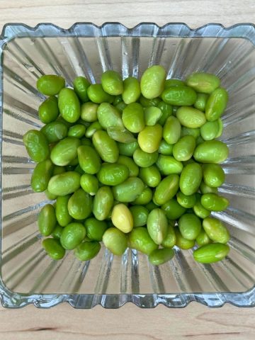 Boiled edamame served in a bowl on a wooden table