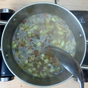 Three cups of hot water added to the spiced vegetable mixture, coming to a boil before adding rava for perfect upma consistency.