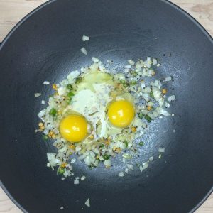 Two raw eggs added to the pan for scrambling
