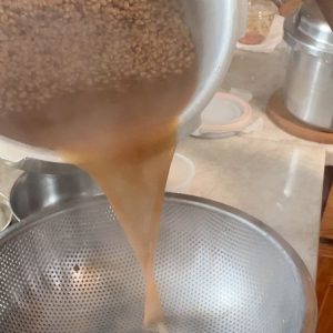 Straining cooked horsegram to separate excess water, highlighting the texture of perfectly cooked ulavalu legumes.