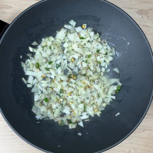 Golden-brown sautéed onions being prepared for the tempered horsegram snack, adding flavor and texture to the dish.