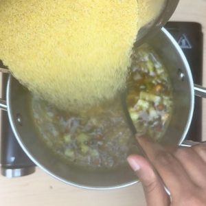 Roasted rava (semolina) being gradually stirred into boiling water, preventing lumps for smooth and fluffy South Indian upma.