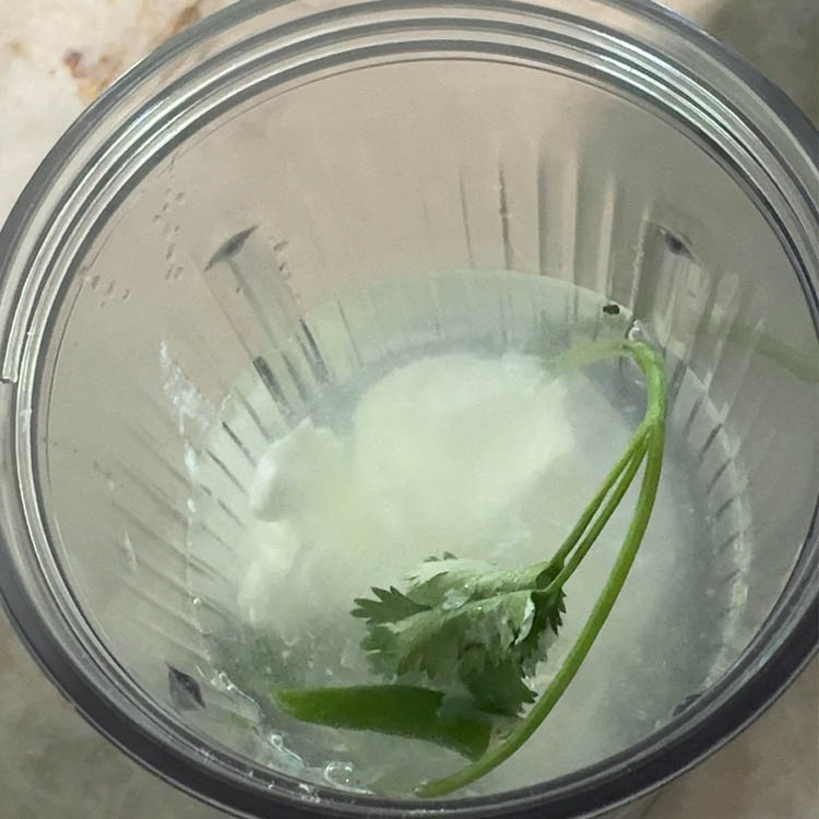 Adding ½ cup of plain yogurt to the blender with spices and water, a key step for creamy, homemade buttermilk.
