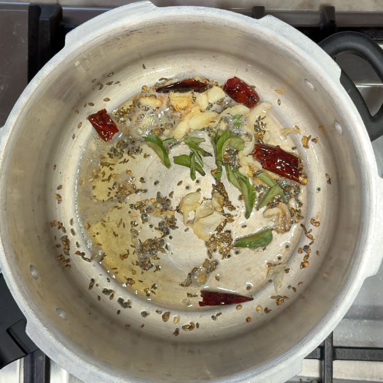 Adding fresh curry leaves to the tempering spices