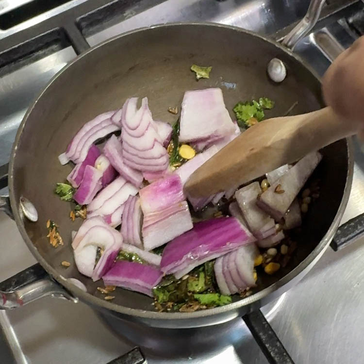 Adding sautéed onions to tempered spices for broccoli eggplant chutney