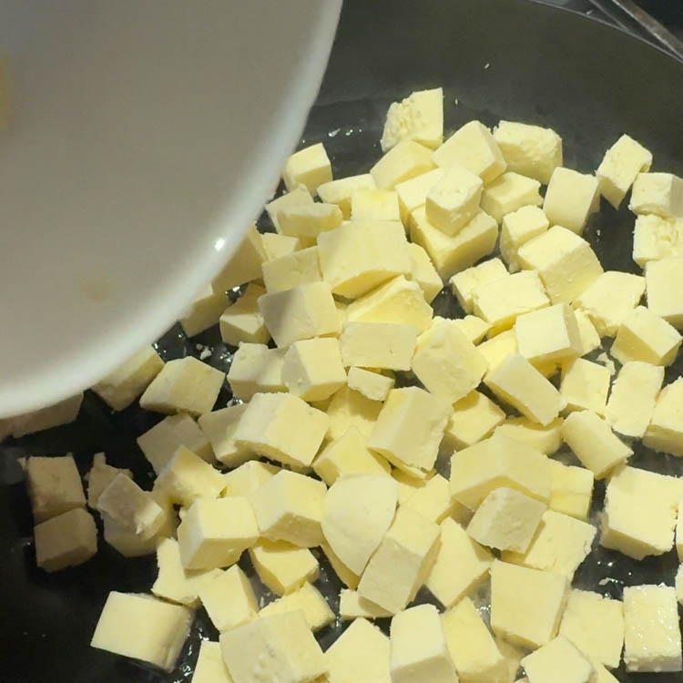 Fresh paneer cubes being added to a hot pan with oil, beginning the Methi Paneer Stir Fry preparation.