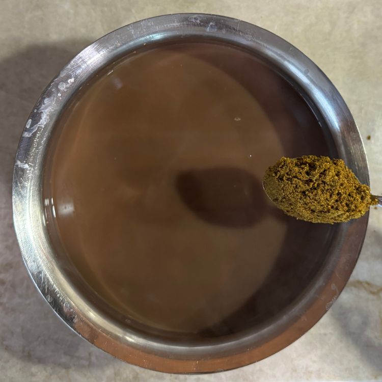 Sprinkling freshly ground spice powder mix into the boiling horsegram water
