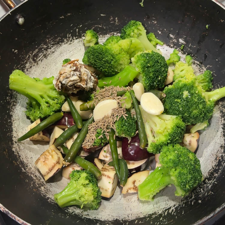Broccoli, eggplant, and spices in a pan ready to cook for flavorful vegetable chutney