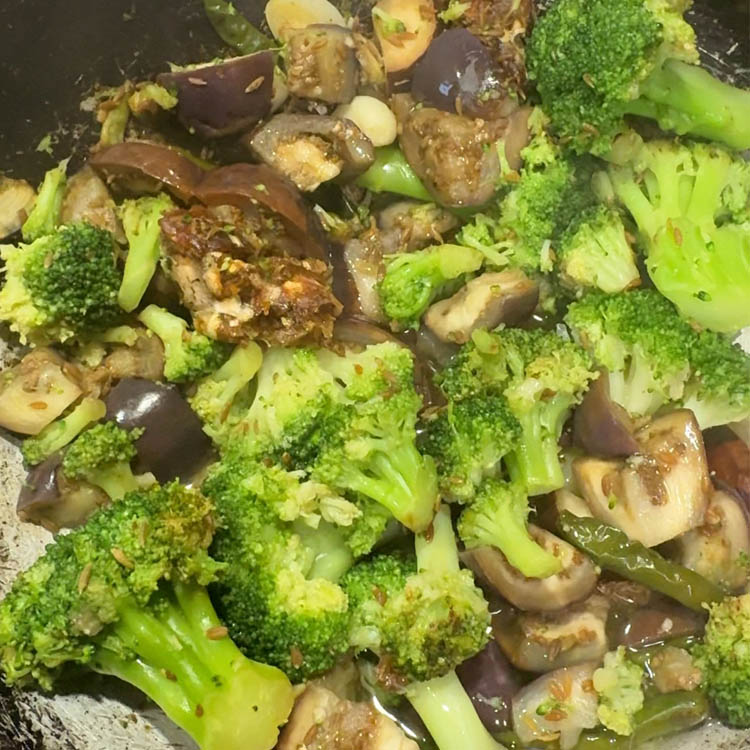 Stirring softened broccoli and eggplant mixture for homemade chutney preparation