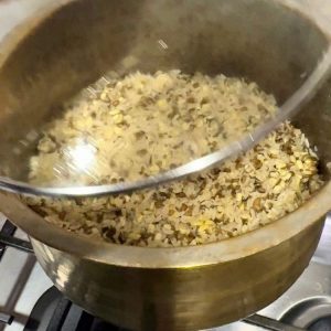Freshly cooked, fluffy high-protein rice with visible grains of white rice and split green moong dal after removing the lid.