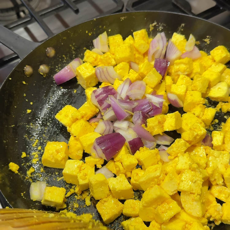 Sliced onions being added to the pan with paneer, a key step in creating a flavorful Methi Paneer Stir Fry.