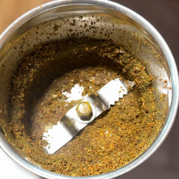 Freshly ground spice mix for Ulavacharu Rasam with black pepper, cumin, and coriander in a blender