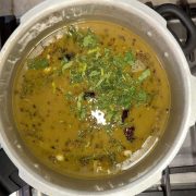 Steaming hot Ulavacharu Rasam served in a traditional brass bowl garnished with fresh cilantro leaves