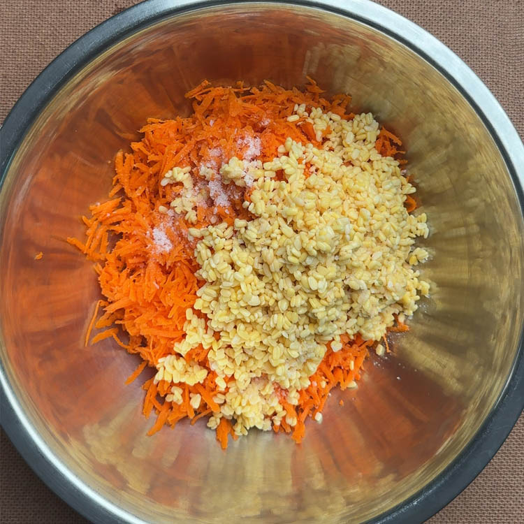 Grated orange carrots mixed with soaked yellow moong dal in a white mixing bowl for South Indian kosambari