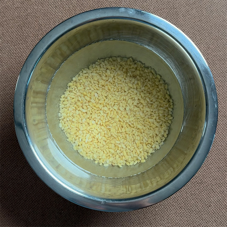 moong dal soaking in a mixing bowl with water on a table
