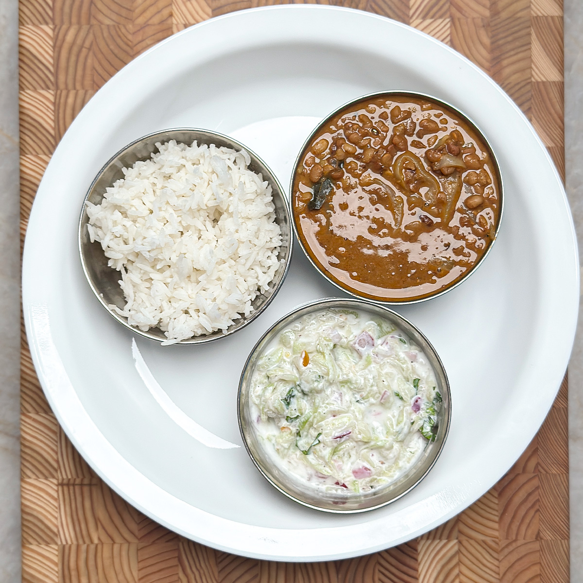 horse gram curry with bottle gourd raita & rice in mini bowls on a plate