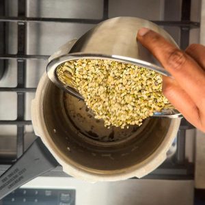 Pouring split green lentils into pressure cooker with ghee
