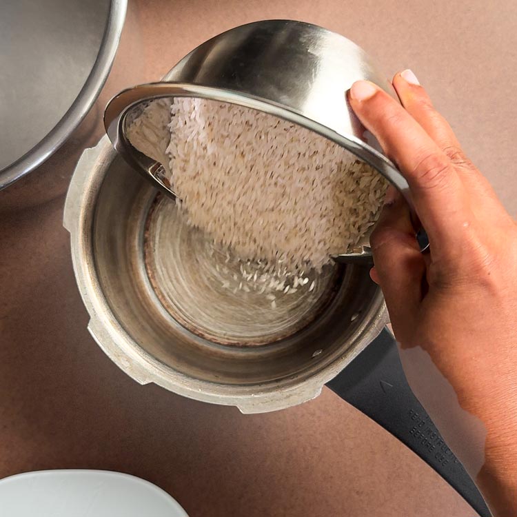 White rice being poured from bowl into pressure cooker pot