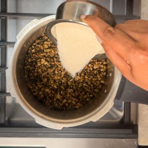 Sprinkling white sugar into mashed cooked lentils in cooker