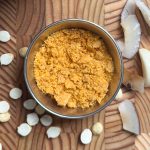 Homemade spice powder served in a polished steel bowl on wooden cutting board with scattered ingredients