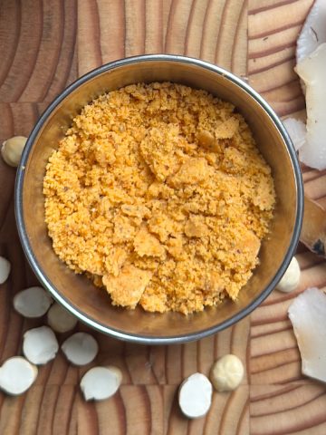 Homemade spice powder served in a polished steel bowl on wooden cutting board with scattered ingredients