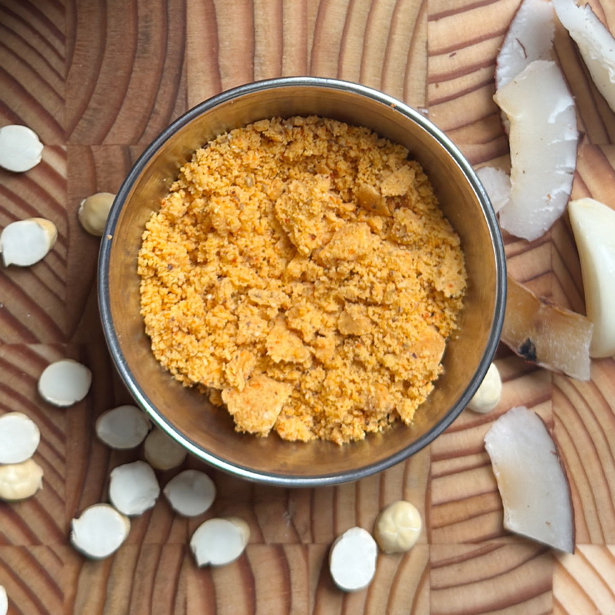 Homemade spice powder served in a polished steel bowl on wooden cutting board with scattered ingredients