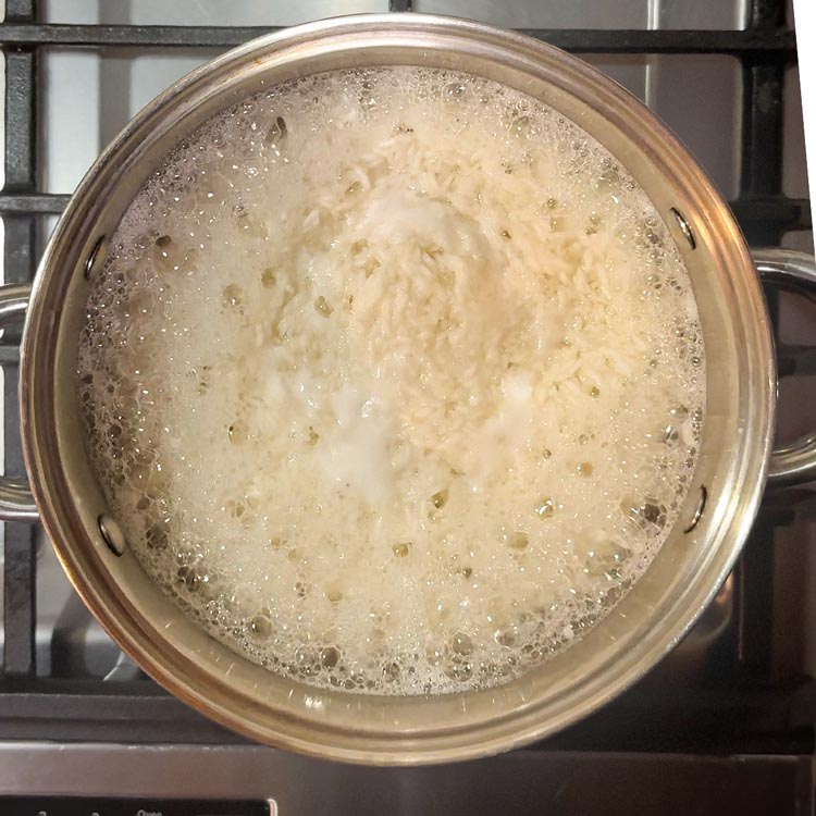 Boiling water reaching the top level of rice grains in pot