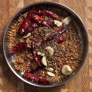 All roasted ingredients - dal, spices, and salt - cooling together on white ceramic plate