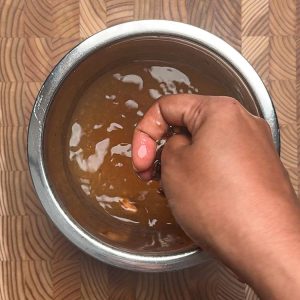 Hand squeezing and straining tamarind pulp through fingers