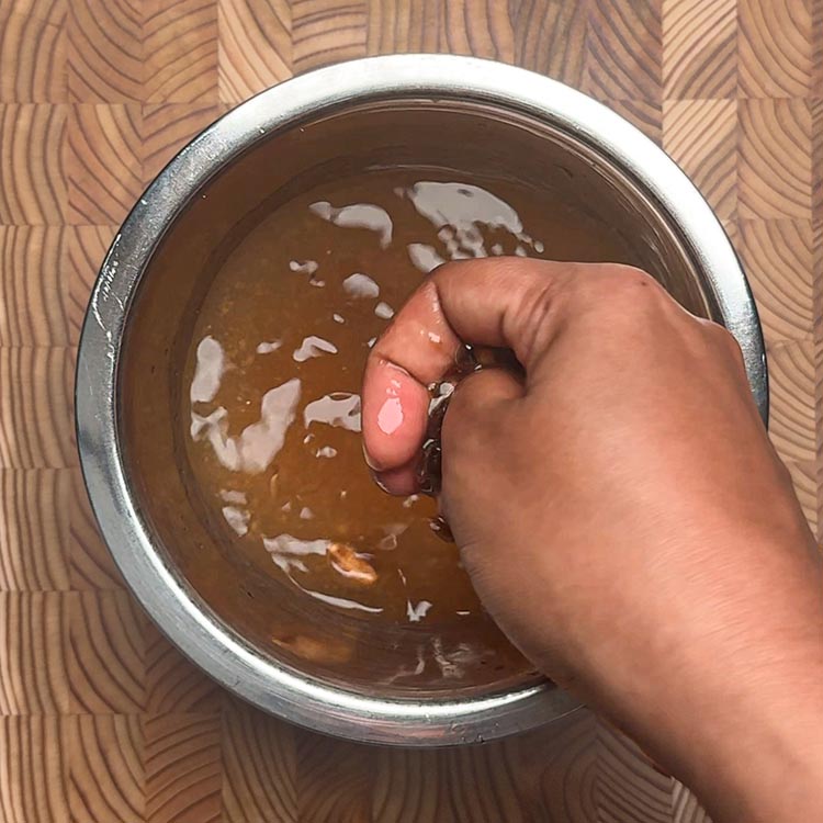 Hand squeezing and straining tamarind pulp through fingers
