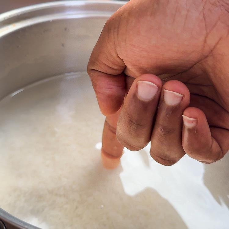 Index finger measuring water level at first knuckle in rice pot