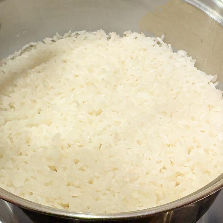 Fluffy white rice freshly cooked in pot with visible steam