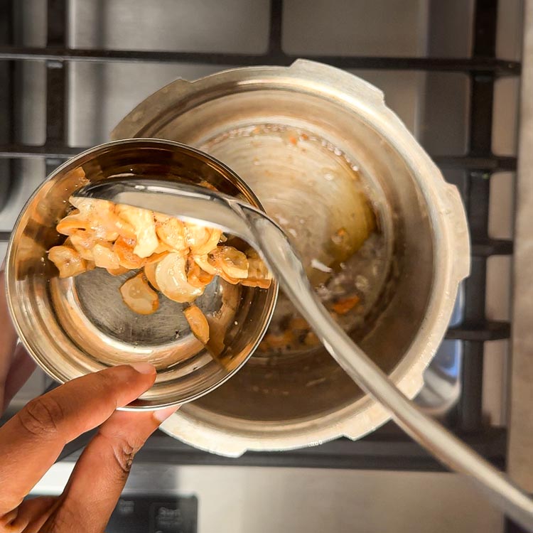 Transferring golden brown roasted cashews to small white bowl