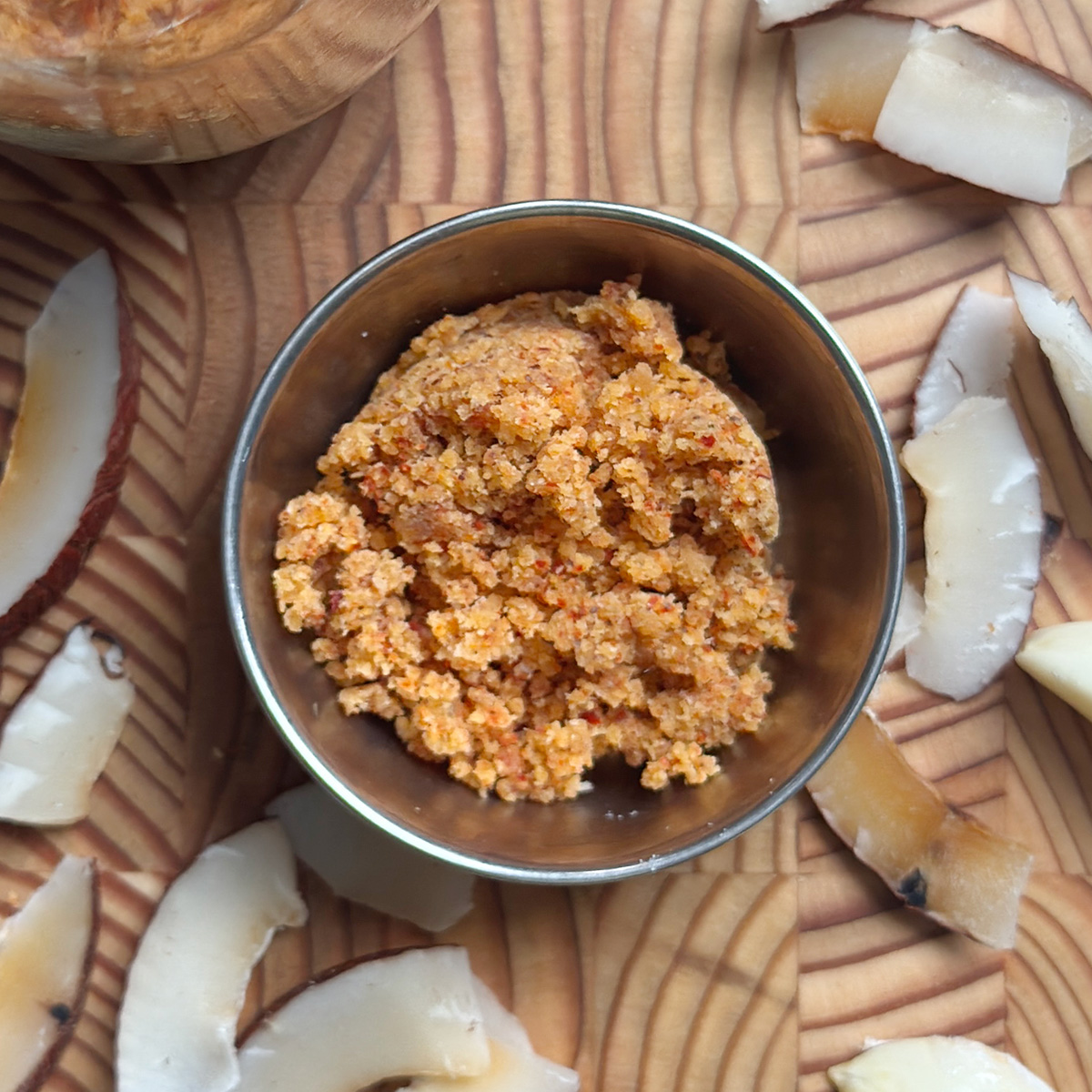 Golden brown coconut garlic podi served in a stainless steel bowl on wooden cutting board