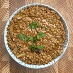 Creamy horse gram curry garnished with fresh herbs in ceramic bowl