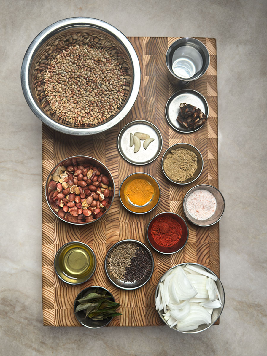 Dried lentils, spices, and fresh vegetables arranged on wooden cutting board
