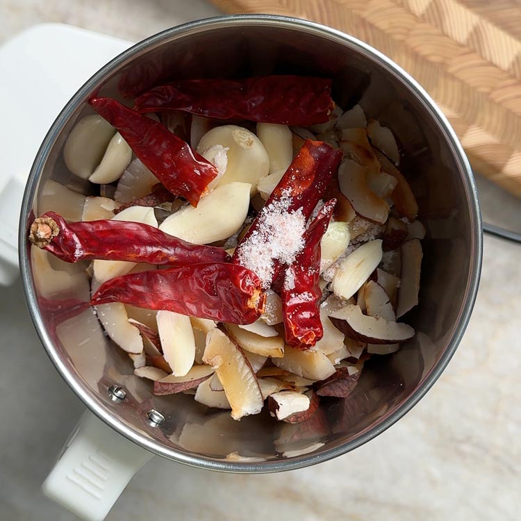 Raw ingredients including coconut, garlic and chilies placed inside an Indian mixi grinder jar