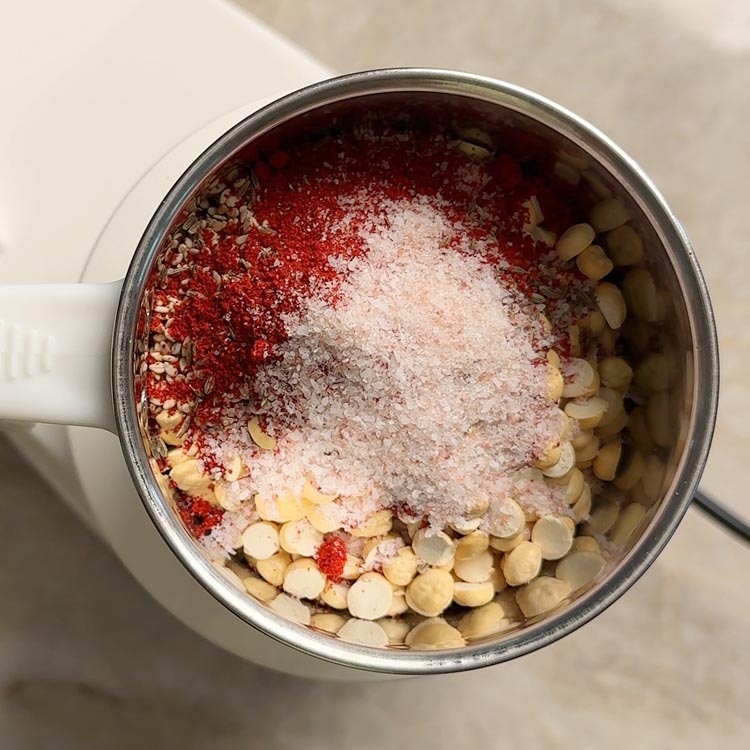Roasted chana dal, coconut slices, and spices loaded in a stainless steel mixi jar ready for grinding