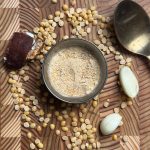 Fine reddish-brown Kandi Podi powder in small ceramic bowl on wooden table, ready to serve with rice
