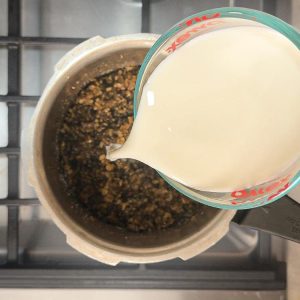 Streaming fresh milk into sweetened dal mixture while stirring