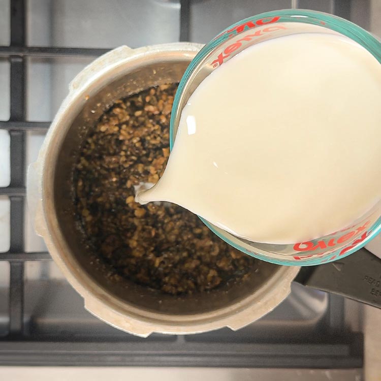 Streaming fresh milk into sweetened dal mixture while stirring