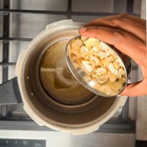 Adding cashew halves to melted ghee in pressure cooker
