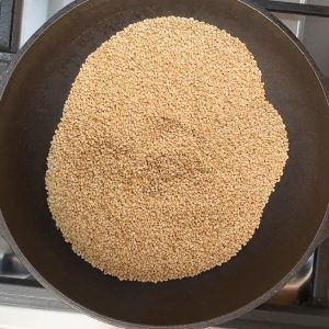 Golden sesame seeds roasting in heavy-bottomed pan