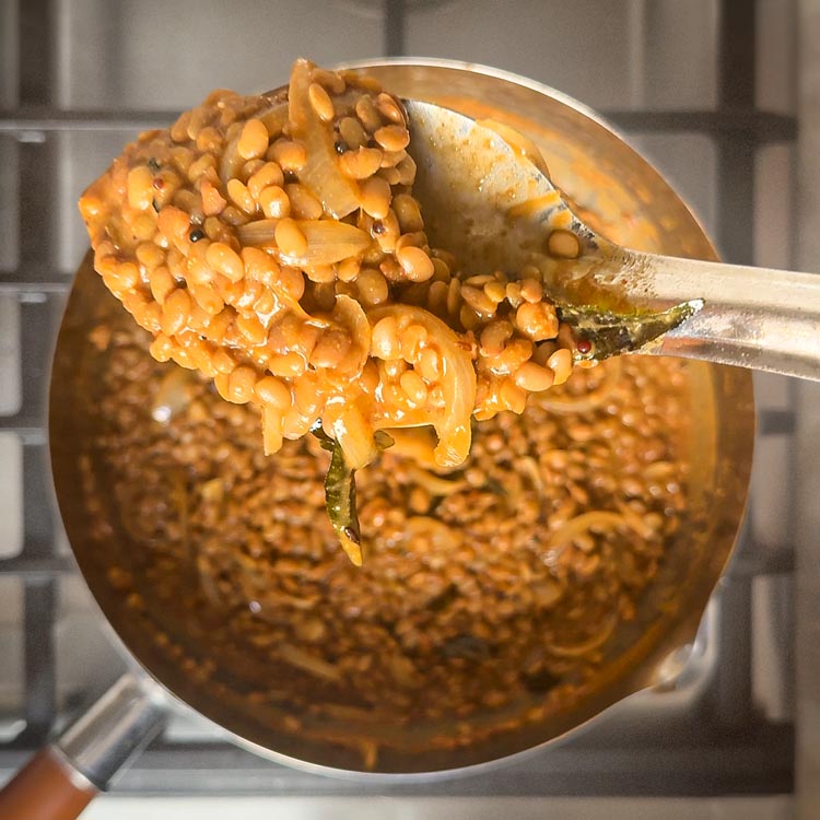 Horse gram curry simmering with visible lentils in rich gravy